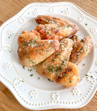 baked chicken wings sprinkled with parsley on white plate