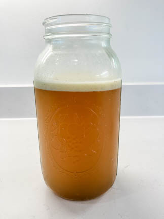 Beef bone broth in glass jar on white counter