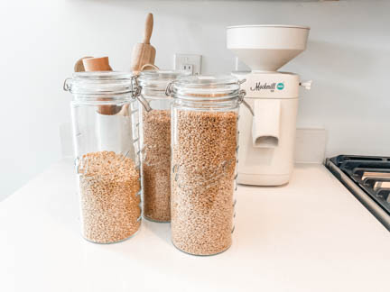 3 glass jars holding bulk wheat berries on white counter