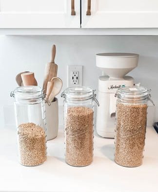 3 glass jars storing wheat berries on white countertop