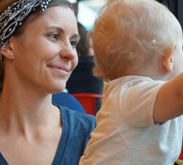 young mom with headband smiling at baby in white shirt