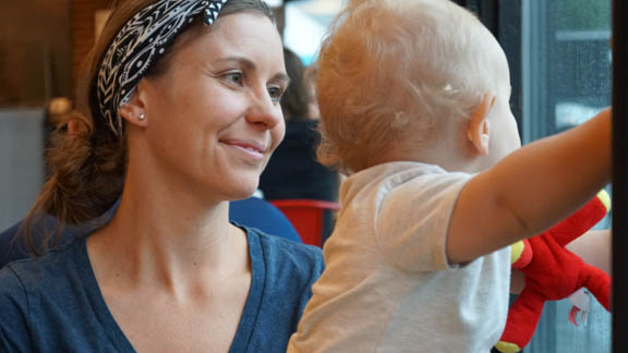 young mom with headband smiling at baby in white shirt