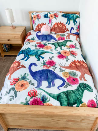 light wooden twin bed frame with watercolor dinosaur pattern bedding