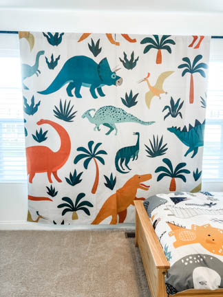 dinosaur curtains hanging from bronze rod on white wall