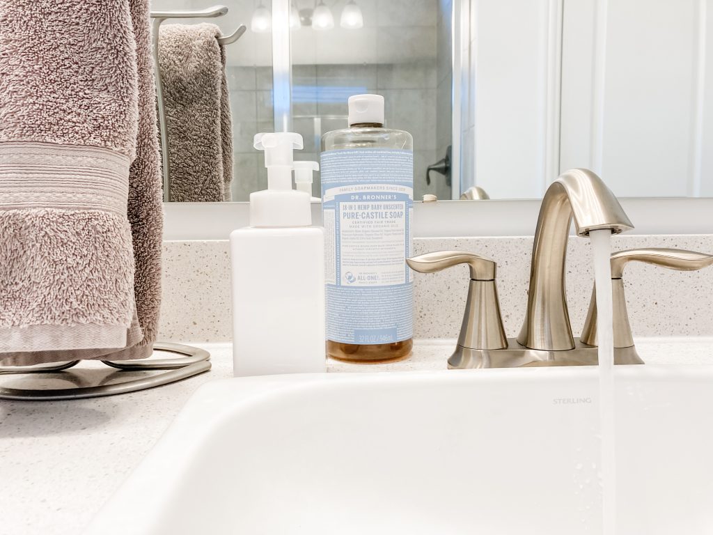 white soap dispenser next to hanging hand towel and silver faucet on bathroom counter