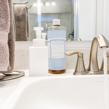 white soap dispenser next to hanging hand towel and silver faucet on bathroom counter